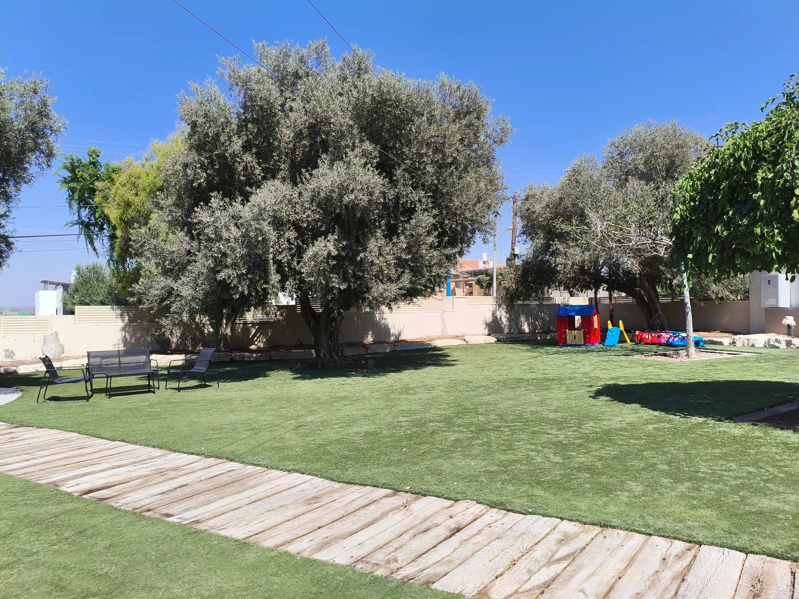 החצר הענקית של אחוזת אלפא עם מדשאה ופינות ישיבה